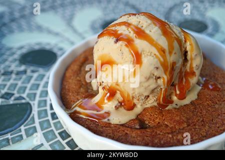 Closeup Mouthwatering Texture of Warm Cookie Topped with Ice Cream and Salted Caramel Sauce Stock Photo