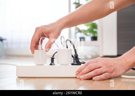 Plugging electrical plug on floor, socket at home. Energy efficiency concept Stock Photo