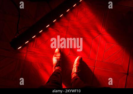 Red light lighting up feet in classic shoes on a wooden floor Stock Photo