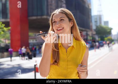 Brazilian business woman records a voice message with her mobile phone in Sao Paulo avenue Stock Photo