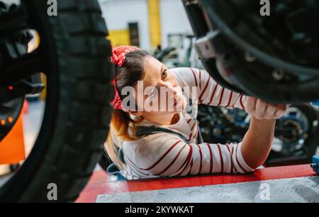 Mechanic woman checking motorcycle on factory Stock Photo