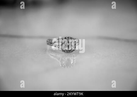 Black and white image of a diamond engagement ring set in platinum on a natural Carrara marble background. Stock Photo