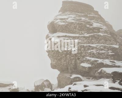 The Sphinx (Sfinxul), a natural rock formation in the Bucegi Natural Park, in the Bucegi Mountains of Romania, during a snowy winter day. Stock Photo