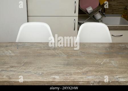 Part of an empty table and two white chairs in a kitchen Stock Photo