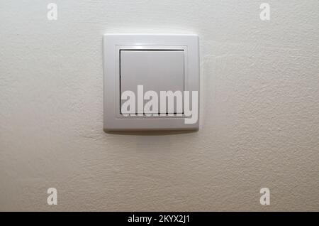 White plastic light switch on a white wall Stock Photo