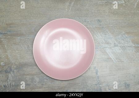 Pink empty plate on a wood pattern surface - top-shot Stock Photo