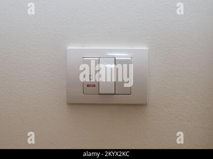 White plastic switch with three switches on a white wall Stock Photo
