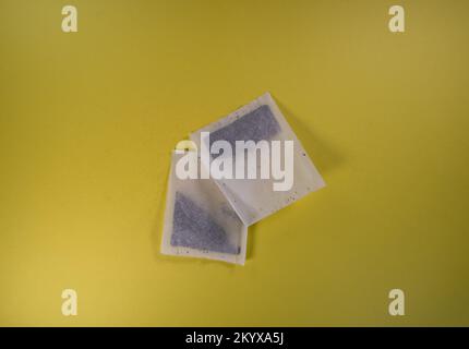 two square tea bags isolated on a yellow background Stock Photo