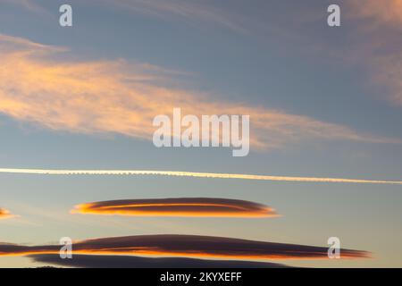Lenticular clouds and cirrus clouds in the sky with the moon at dawn Stock Photo