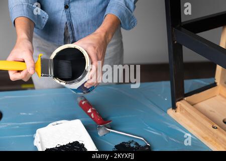 Young women preparing to restore a stepladder for children as a hobby house improvement. On a covered table. Painting with brush Stock Photo