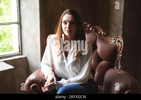 Portrait of business lady in office industrial style while sitting on vintage office armchair Stock Photo
