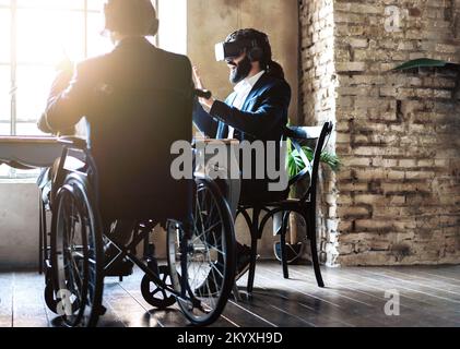 African disabled businessman working with new wearable technology with his colleague during business meeting at office Stock Photo