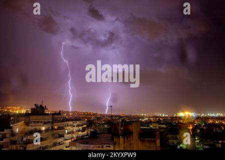 night city view under thunderstorm with strike of lightning. Powerful thunderbolt during thunderstorm in the city. Cloud to ground electric lightning Stock Photo