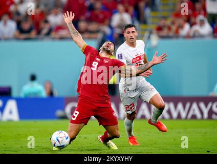 Serbia's Aleksandar Mitrovic (left) goes down whilst battling for the ball with Switzerland's Fabian Schaer during the FIFA World Cup Group G match at Stadium 974 in Doha, Qatar. Picture date: Friday December 2, 2022. Stock Photo