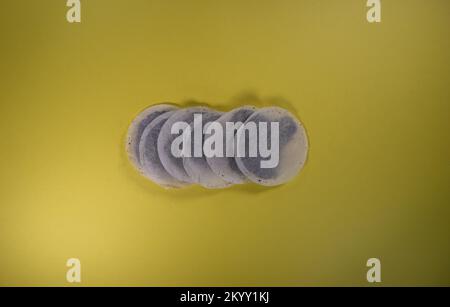 line of six round tea bags isolated on a yellow background Stock Photo