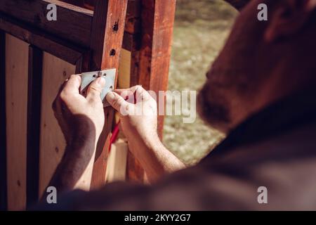 Handyman placing a door hinge in the wooden door frame. Home renovation Stock Photo