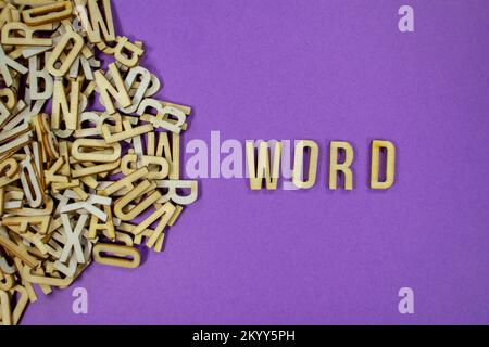 purple background with a pile of wooden capital letters spilling into words - WORD Stock Photo