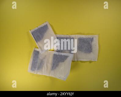 two and a half pairs of square tea bags isolated on a yellow background Stock Photo