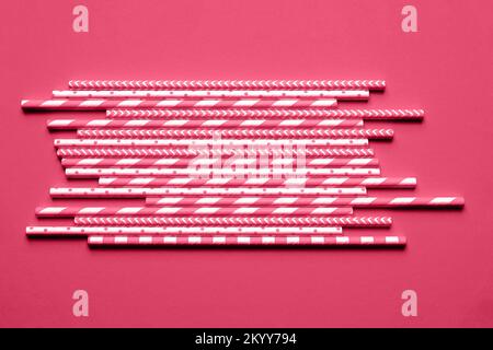 Pink paper party straws on viva magenta background. Color trend of the year 2023. Stock Photo