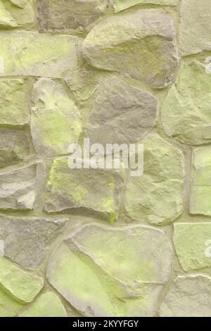 Neon yellow spray painted rough stone wall wallpaper. Vertical layout 5k Stock Photo
