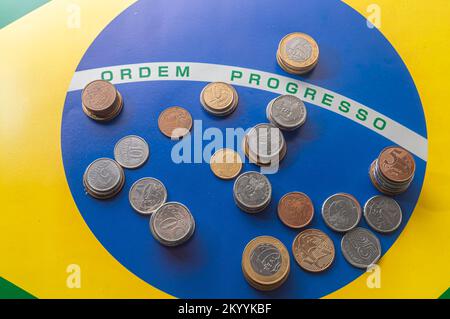 Translation 'order progress'Brazilian flag with Brazilian real coins,concept of decay of Brazilian money. Stock Photo