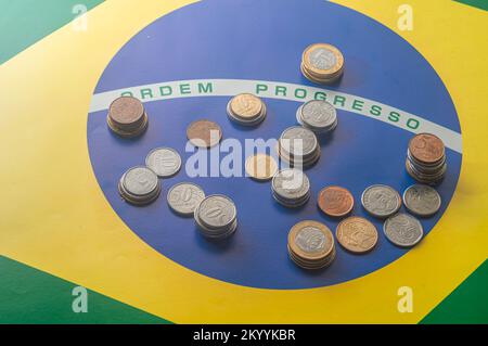 Translation 'order progress'Brazilian flag with Brazilian real coins,concept of decay of Brazilian money. Stock Photo