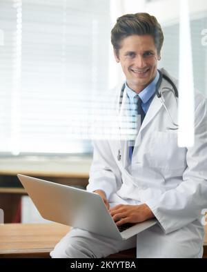 My office is always open to patients. Through the window shot of a young doctor working on a laptop. Stock Photo