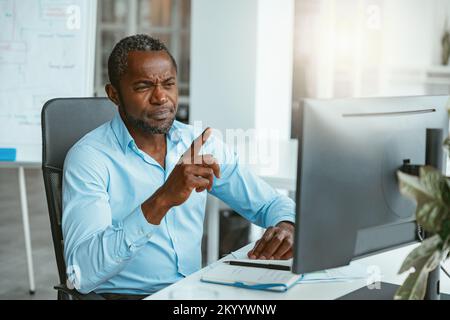 Busy african businessman working on computer while sitting in modern coworking Stock Photo