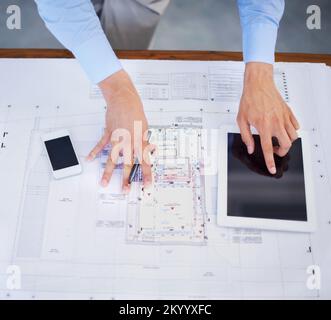 Using technology to perfect his work. Top view image of an architect using his tablet to perfect his blueprints. Stock Photo
