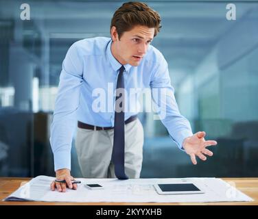 Lets work together on this. An experienced young architect explaining his blueprints to colleagues - off screen. Stock Photo