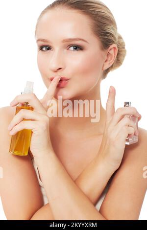 Dont tell anyone about my beauty secrets...A gorgeous young woman with a finger to her lips while holding her beauty products. Stock Photo