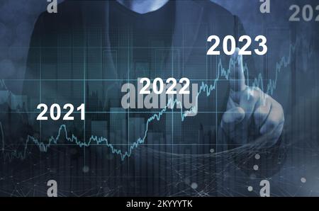 economic recovery after falling due to inflation, stagnation, recession, 2023 financial chart. Businessman pointing graph of future growth on dark blu Stock Photo