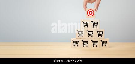 Sale volume increase. Hand putting cube with target and arrow to top of sales pyramid. Wood cube with icon goal and shopping cart symbol. Business ach Stock Photo