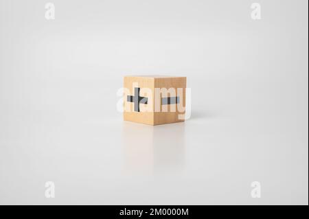 wood cube with plus and minus on gray background. opposites concept. analysis of good and bad. pro and con. Stock Photo