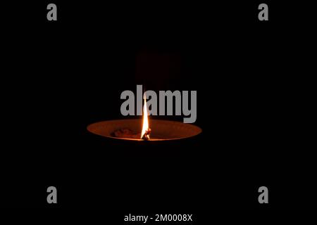 A rope in oil lies on a plate and burns in the dark, a homemade candle at home in the dark Stock Photo