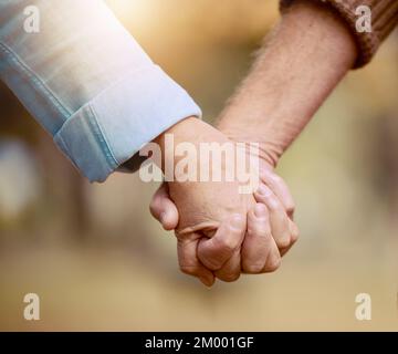 Senior couple, holding hands and walking in nature to bond in the countryside for love, care and affection. Retirement, hands of elderly husband and Stock Photo