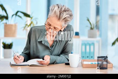 Writing, notebook and schedule with a woman ceo, manager or boss checking her diary for an appointment. Calendar, coffee and notes with a senior Stock Photo