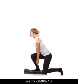 Crouching on her exercise mat. A pretty young woman balancing on her rolled up exercise mat - isolated. Stock Photo