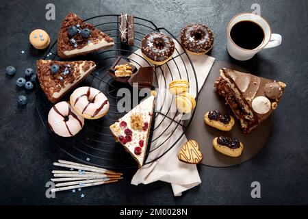 Table with various cookies, donuts, cakes, cheesecakes on dark background.  Delicious dessert table. Top view, flat lay Stock Photo