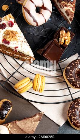 Table with various cookies, donuts, cakes, cheesecakes on dark background.  Delicious dessert table. Top view, flat lay Stock Photo