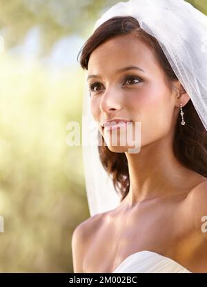 Facing her future. Gorgeous young bride looking away in her wedding dress and veil. Stock Photo