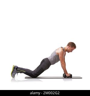 Press-ups with dumbbells. A fit young man doing push-ups with a pair of dumbbells. Stock Photo