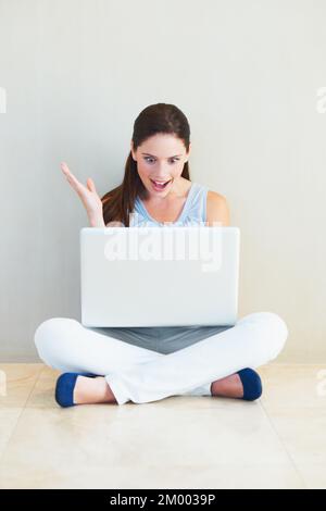 I cant believe it. A pleasantly surprised young woman gasping while looking at her laptop screen. Stock Photo