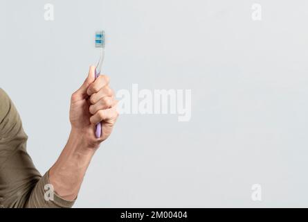 Hand holding toothbrush isolated on white. Male hand showing a toothbrush isolated. Toothbrush concept Stock Photo