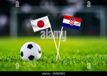 Japan - Croatia Eight final, Last 16 football match. Round of 16. Handmade national flags and soccer ball on green grass. Football stadium in backgrou Stock Photo