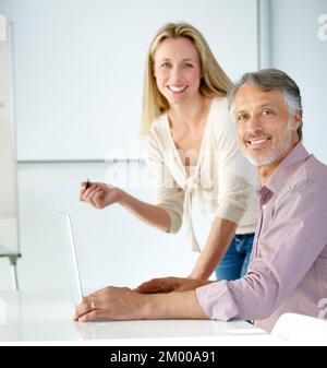 Years of creative genius working together. Portrait of two mature designers working on a laptop and smiling at the camera. Stock Photo