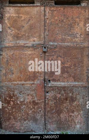 Ancient rusty iron door closed by a padlock Stock Photo
