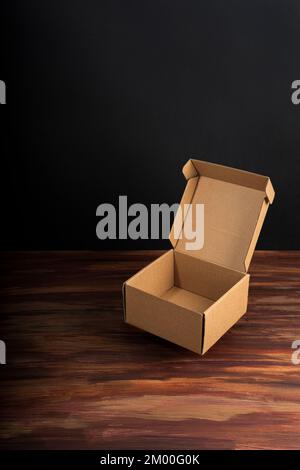 Cardboard box on a dark rustic wooden background in vertical view with copy space Stock Photo