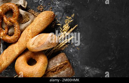 Fresh baked bread assortment on black textured board background. Top view Stock Photo