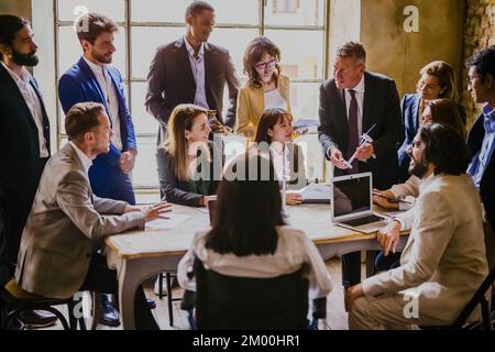 Young and adult business people discussing about financial investments on wind energy and the green economy, diverse people working on sustainability Stock Photo